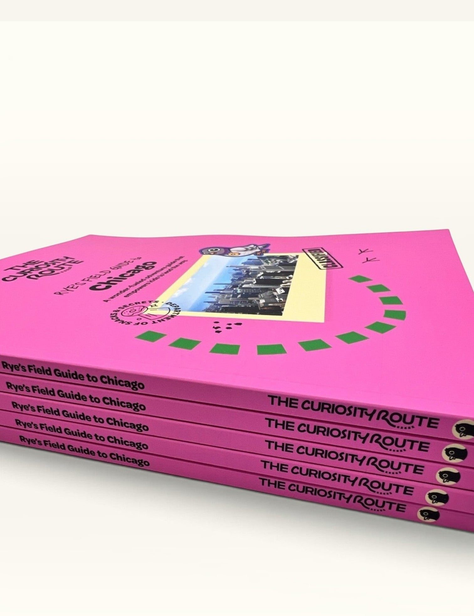 A stack of The Curiosity Route Rye's Field Guide to Chicago books with bright pink covers and illustrated pigeon mascot.