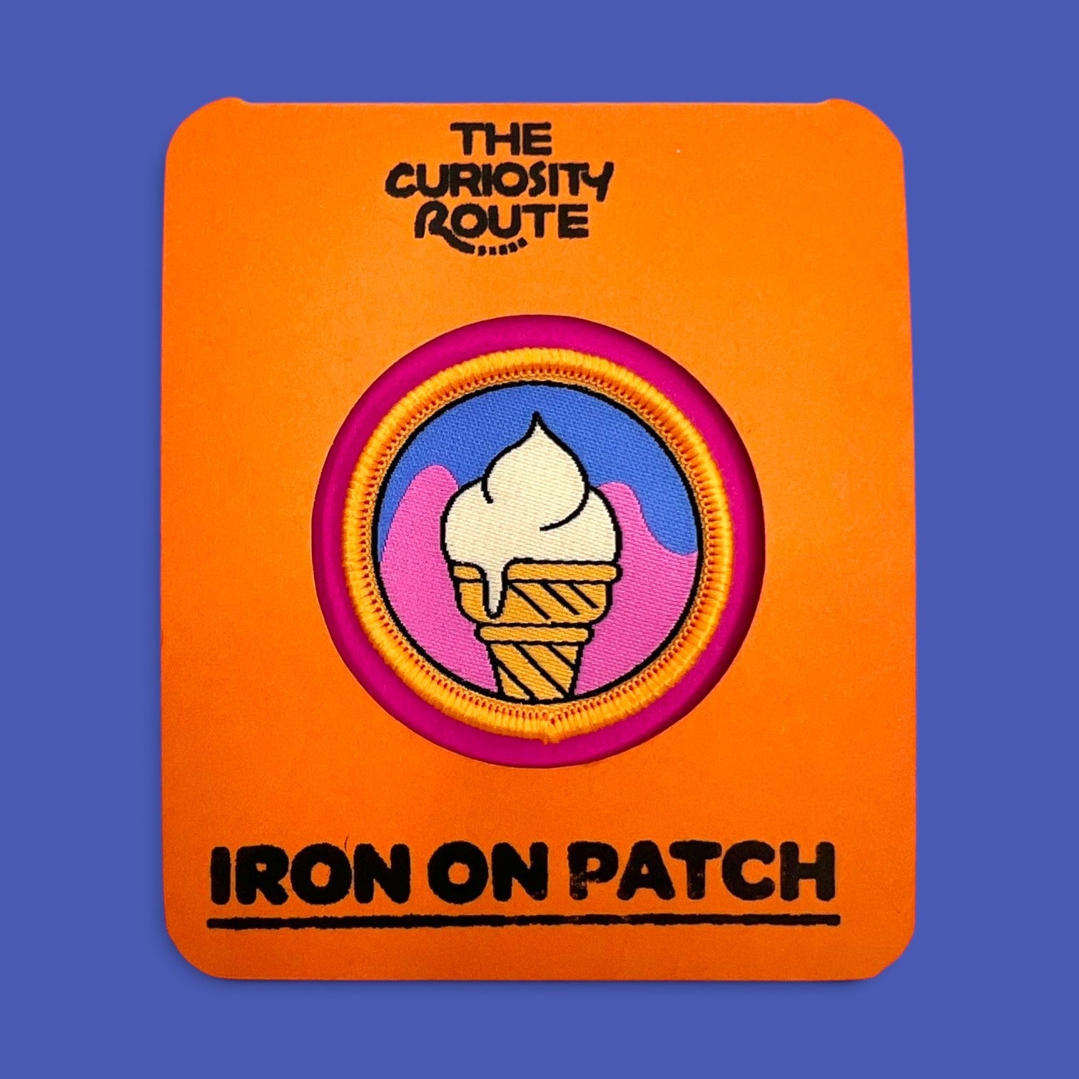 The Curiosity Route Cone Recon woven iron-on patch featuring a white ice cream cone on a blue and pink background.