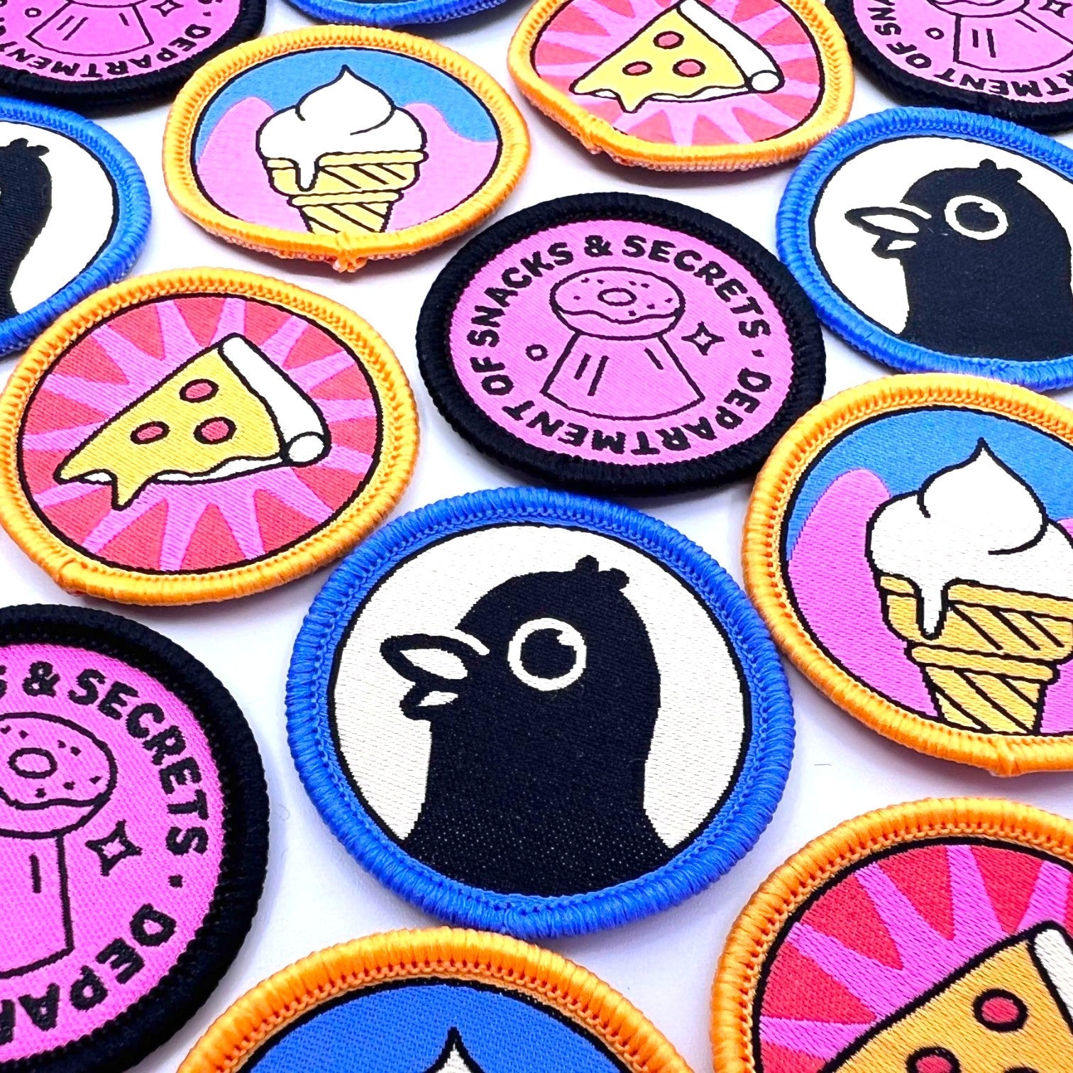 The Curiosity Route Slice Squad iron-on woven pizza patch featuring a colorful pizza slice design on a pink background